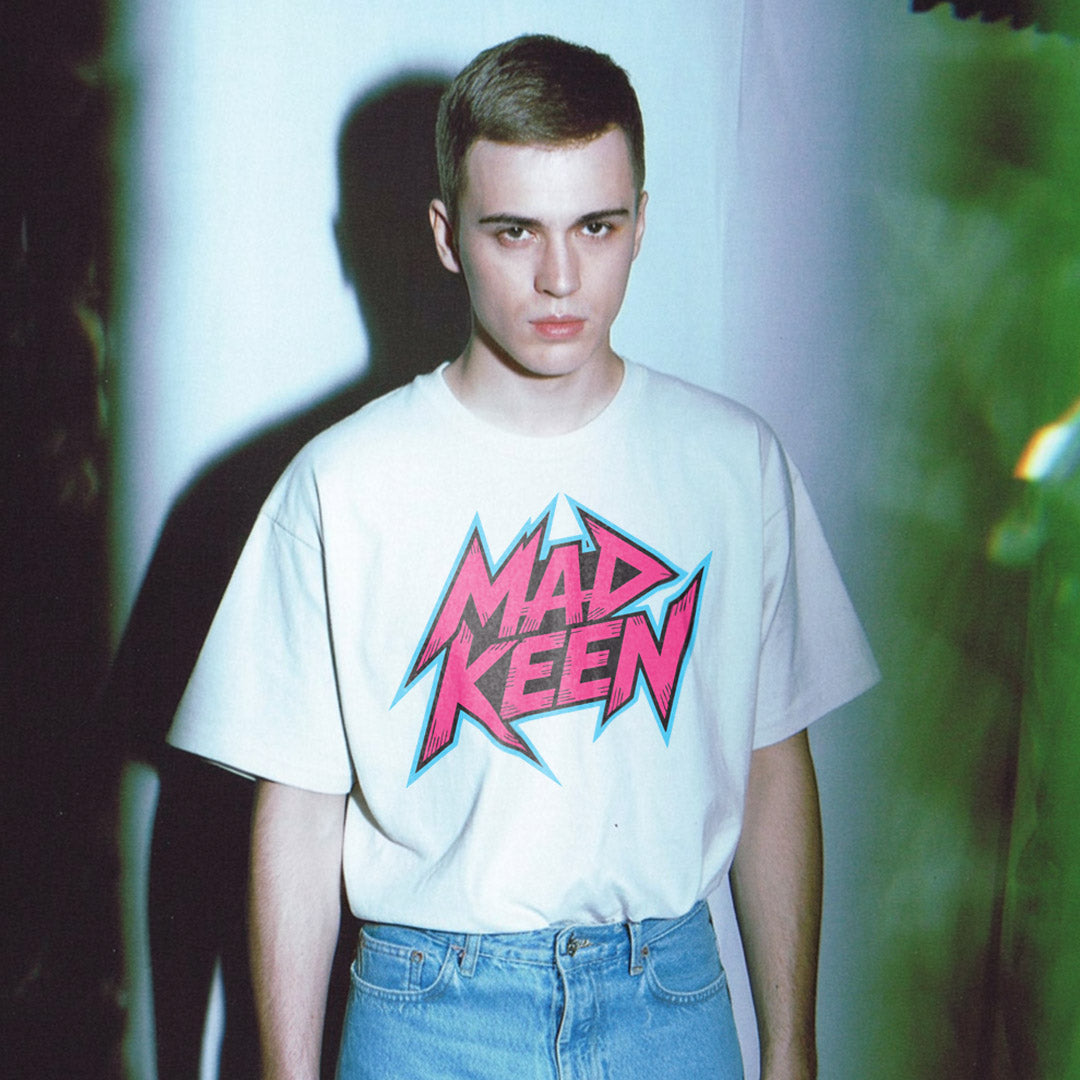Person wearing a white t-shirt with 'Mad Keen' graphic design against a white background